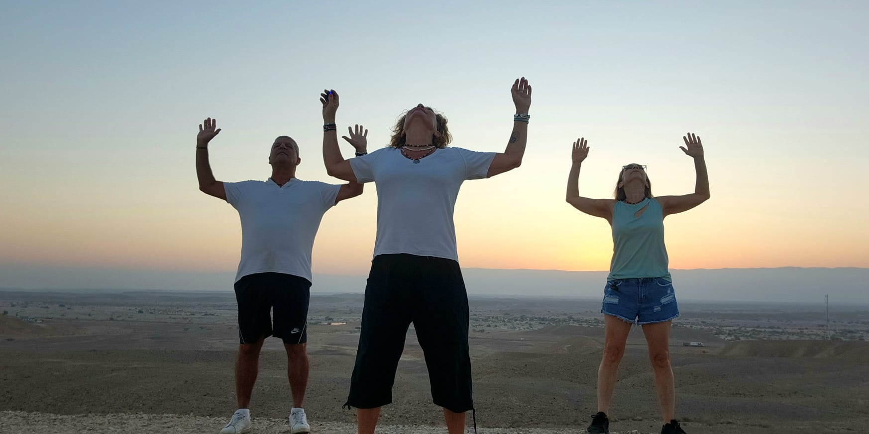 תרגול צ'יקונג בזריחה במדבר — ידיים פתוחות אל השמיים